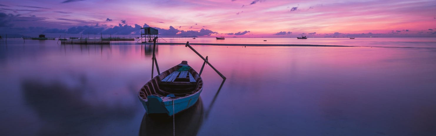 a boat on a lake with a blue pink and purple sunset